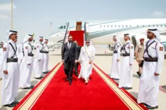 O presidente sírio Ahmed al-Sharaa caminha sobre um tapete vermelho após desembarcar de um avião em Doha, antes de uma cúpula emergencial de líderes árabes e islâmicos.