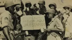 Soldados segurando cartaz em que se lê: Hitler, aqui já estamos
