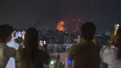 Жители Бейрута наблюдают за пожарами, возникшими в результате ночных ударов Израиля по инфраструктуре «Хезболлы»