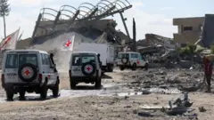 যুদ্ধের সময় ইসরায়েলে আটক ফিলিস্তিনিদের মৃতদেহ বহনকারী একটি ট্রাককে রেড ক্রসের যানবাহন পাহারা দিচ্ছে।