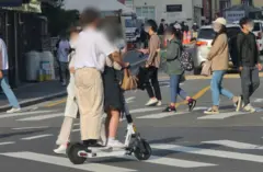 두 사람이 헬멧 없이 한 전동킥보드를 타고 있는 무습