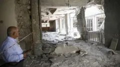 Un hombre observa los daños en el interior del Parlamento turco tras el ataque con helicópteros ocurrido el 15 de julio de 2016. Se aprecia un gran agujero en una pared, con ventanas destrozadas, cristales rotos y escombros esparcidos por todo el edificio.