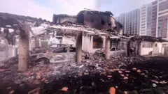 Carros queimados e destruídos no que parece ter sido um estacionamento.