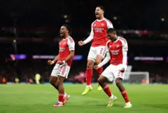 Arsenal players Jurrien Timber, William Saliba and Cristhian celebrate dia first goal against Bayern Munich - 26 November 2025