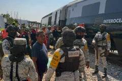 Miembros de la Guardia Nacional y rescatistas, uniformados, al lado del accidente al lado del tren
