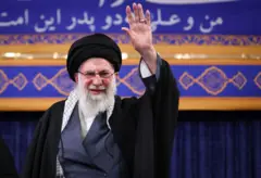 Ali Khamenei com a mão levantada acenando para pessoas
