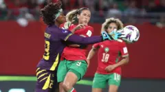 Cameroon goalkeeper Michaely Biniha try to save di ball as two Morrocan players dey come near her.