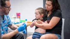 Un médico vacuna a una niña en Texas