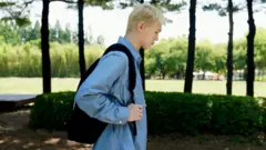 Bain de perfil caminhando em parque com mochila nas costas