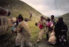 Çocukları helikoptere taşıyan kişiler 