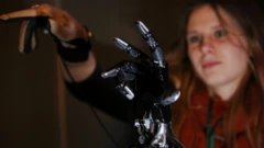 Uma mulher demonstra uma mão robótica.