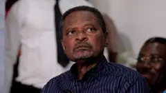 Cameroonian politician Anicet Ekane wear blackwit white strip shirt