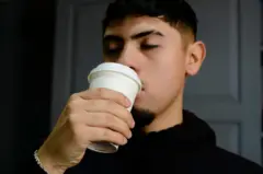 Rapaz tomando café em um copo de papel