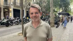 Homem de pé, em uma rua de Barcelona, na Espanha.