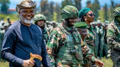 Corneille Nangaa wambaye ingofero ya gisirikare n'ishati y'ubururu bwijimye, Sultani Makenga wambaye ingofero n'imyenda ya gisirikare na Bernard Byamungu iruhande rwe