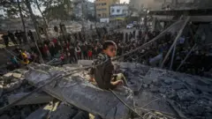 طفل فلسطيني يجلس على الأنقاض بعد الغارات الجوية الإسرائيلية على مخيم النصيرات للاجئين وسط غزة
