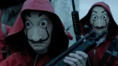 Cena do filme La Casa de Papel em que pessoas aparecem usando vermelho, com máscaras e segundo armas
