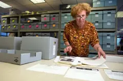Mulher organizando papéis em mesa