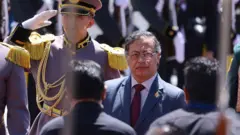 Gustavo petro de pie entre varios militares que realizan un saludo oficial.