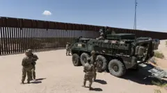 Militares dos Estados Unidos em frente à fronteira com o México. Há um caminhão de guerra.
