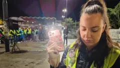 Devojka drži telefon u ruci, upaljeno je svetlo na njemu