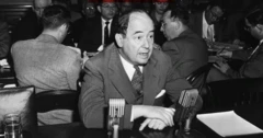Imagem em preto e branco de John von Neumann vestindo um terno e sentado à mes
