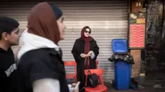 تحمل امرأة إيرانية شابة زهوراً وتقف على رصيف أحد الشوارع في شمال طهران، إيران، في 31 ديسمبر/كانون الأول 2025، في أعقاب أحدث موجة اضطرابات في البلاد. واندلعت احتجاجات في طهران بسبب المشكلات الاقتصادية وانهيار العملة الوطنية. (تصوير: مرتضى نيكوبازل/نورفوتو عبر غيتي إيماجز)