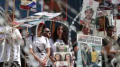Familias de rehenes israelíes sosteniendo sus fotos en una manifestación para exigir su liberación.
