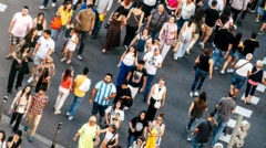 Dziesiątki osób, głównie młodych, przekraczają ruchliwą ulicę w ciepły, słoneczny dzień.