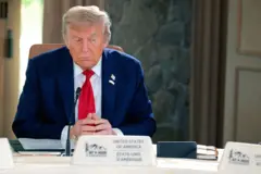 El presidente de Estados Unidos, Donald Trump, asiste a una reunión con los líderes del G7 en la Cumbre de Líderes del G7, el 16 de junio de 2025, en Kananaskis, Alberta. Vestido con traje azul marino, corbata roja y un pin de EE.UU., se sienta a la mesa con las manos cruzadas