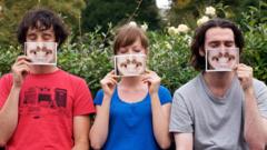 Two men and a woman hold up photographs of their mouths in front of their faces