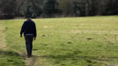 رجل يسير بمفرده وسط أرض خضراء 