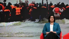 BBCのテレビスタジオに座るマムード内相。背景には、海を小型ボートで渡る人たちが蛍光オレンジの救命胴衣を着け、海辺で波間の中に立つ画像が映し出されている