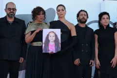 من اليسار: الممثل عامر حليحل، المخرجة كوثر بن هنية، الممثلة سجى كيلاني، الممثل معتز ملحيس، والممثلة كلارا خوري، يقفون أمام صورة الفتاة الفلسطينية هند رجب على السجادة الحمراء لفيلم "صوت هند رجب" في مهرجان البندقية السينمائي