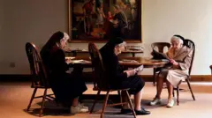 Três freiras lendo num convento em foto de maio de 2001