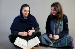 دو زن با حجاب و بی‌حجاب مقابل قرآن نشسته‌اند