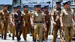 Police walk along a street leading to the Colombo Fort magistrate's court in Colombo on August 26, 2025