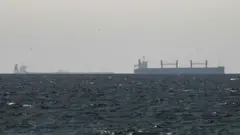 A cargo ship is seen on the horizon in the Gulf, near the Strait of Hormuz