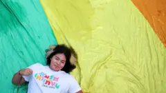 သက်တံ့ရောင်အလံပေါ် လှဲလျောင်းနေတဲ့ အမျိုးသမီးတစ်ဦး 