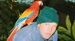 Tom'un ormandaki bir fotoğrafı. Omzunda bir papağan var.