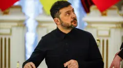 Владимир Зеленский сидит за столом и смотрит влево вверх