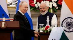 Путин и Моди пожимают друг другу руки на фоне флагов России и Индии.