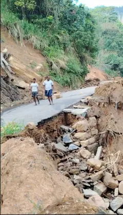 මාර්ගයක් නාය ගොස් ඇති අතර පාර කැඩී ගිය ප්‍රදේශයක් පසු කර පුද්ගලයින් දෙදෙනෙක් ගමන් කරයි.  