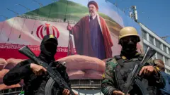 اعضای نیروهای امنیتی ایران در مراسم بزرگداشت چهلمین روزی که حملات مشترک آمریکا و اسرائیل، علی خامنه‌ای، را به قتل رساند، زیر تصویر بزرگی از مجتبی خامنه‌ای، رهبر جدید ایران، نگهبانی می‌دهند.