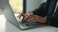 ላብቶፕ ላይ የሚጽፍ እጅ