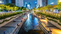 Rio Cheongyecheon, em meio à cidade de Seul, com pessoas andando nas suas margens