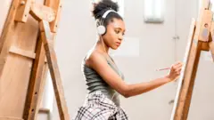 Mulher negra pintando em cavalete