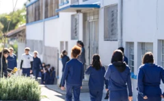 Estudantes andam em escola cívico-militar, de costas, com uniforme azul