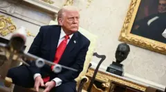 Presidente americano Donald Trump olha para o lado, sentado na Casa Branca