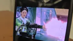 手機展示網上影片中《甄嬛傳》主角鈕祜祿·甄嬛以機關槍掃射的AI生成畫面